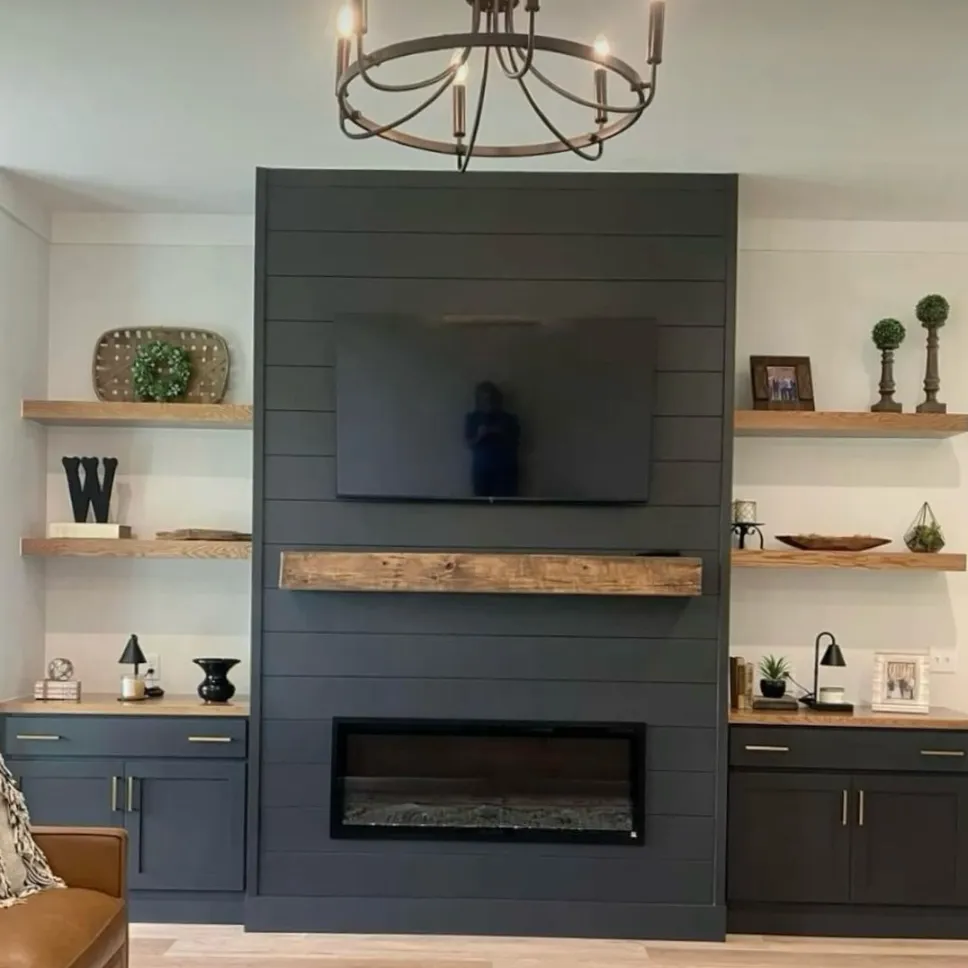 Modern farmhouse living room with a dark charcoal shiplap fireplace surround, electric fireplace insert, and rustic oak floating shelves
